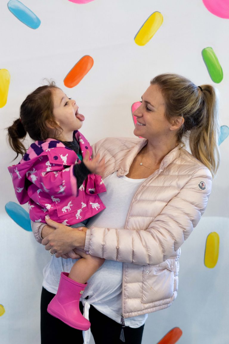 Mom and toddler posing silly in front of the sprinkled donut wall